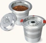 Two PodKupper stainless steel pods, one filled with ground coffee, lids off