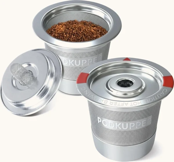 Two PodKupper stainless steel pods, one filled with ground coffee, lids off